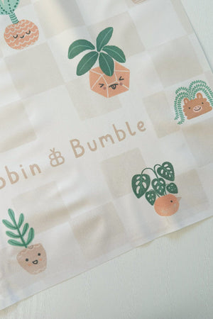 Splash Mat, Pot Plants: corner close-up showing the smiling plant pot print on a beige checkerboard background