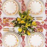 Pretty in Pink Scalloped Lunch Plates on white-edged placemats around a table set with yellow flowers, seen from above
