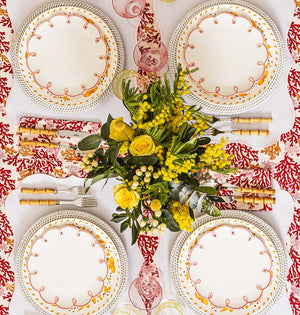 Pretty in Pink Scalloped Lunch Plates on white-edged placemats around a table set with yellow flowers, seen from above
