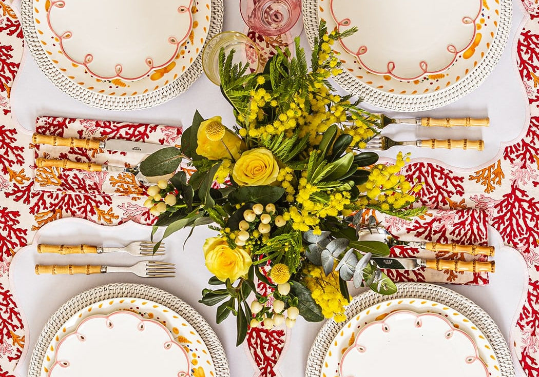 Pretty in Pink Scalloped Lunch Plates on white-edged placemats around a table set with yellow flowers, seen from above