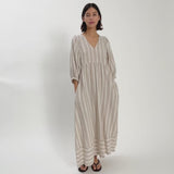 Woman wearing light coloured linen v neck dress moving around