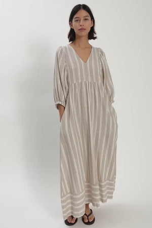 Woman wearing light coloured linen v neck dress moving around