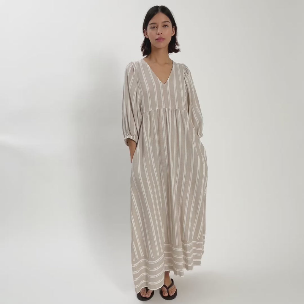 Woman wearing light coloured linen v neck dress moving around