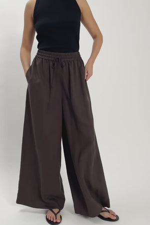 Video of woman wearing brown drawstring trousers moving on the spot