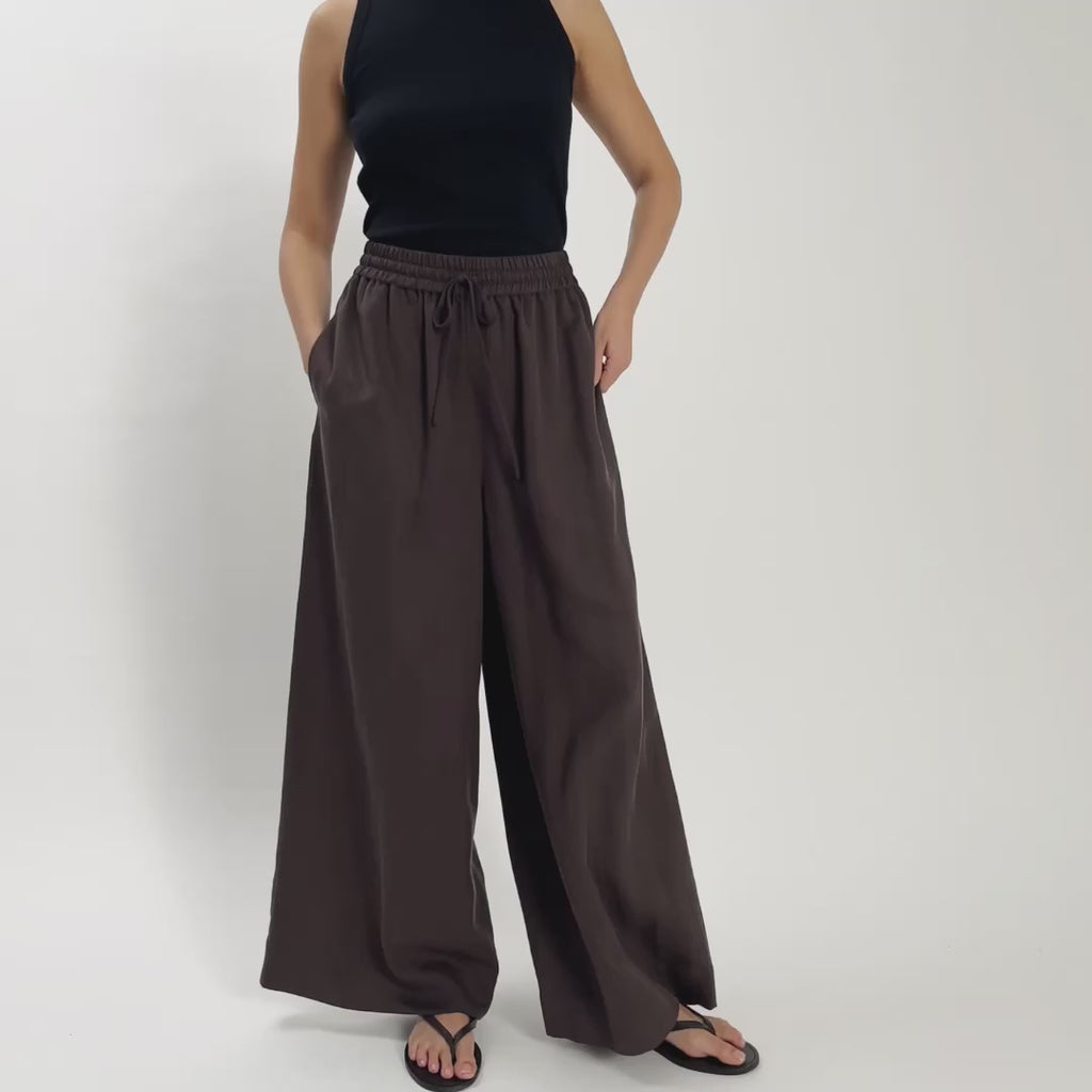 Video of woman wearing brown drawstring trousers moving on the spot