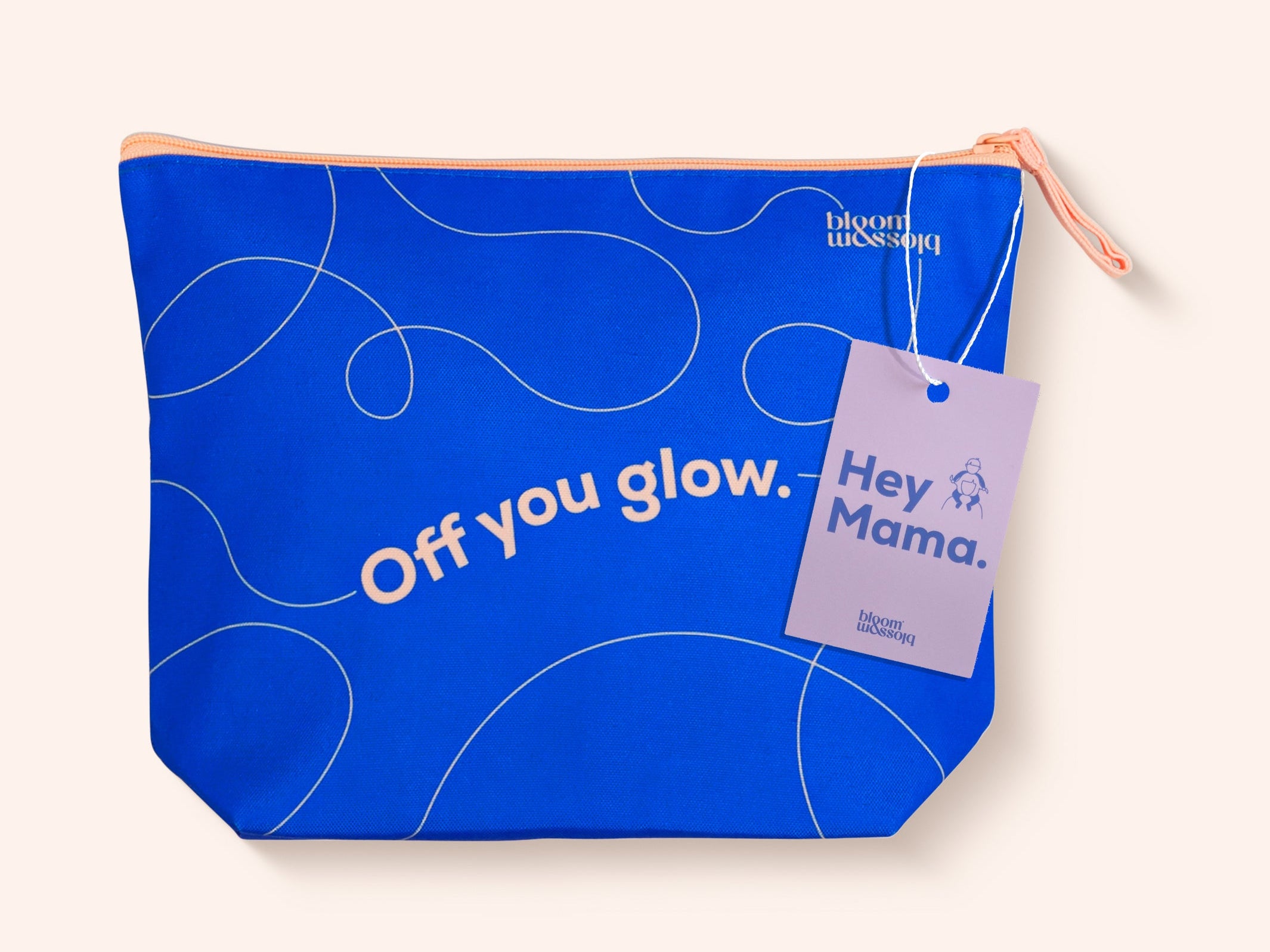 A bright blue zippered pouch with white abstract line drawings and the text 'Off you glow.' on the front, featuring a lavender hangtag that reads 'Hey Mama.