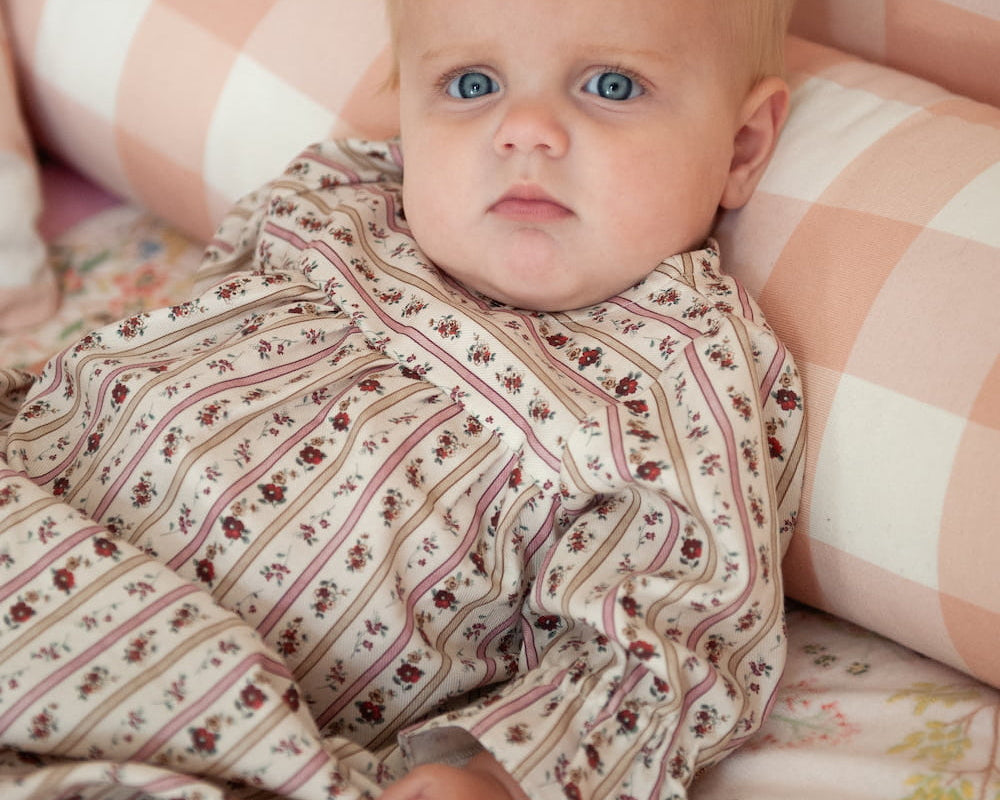 Beatrice Rose Stripe baby nightie close up of ruffled sleeve and floral stripe print on baby resting against cushions