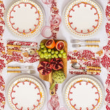 Rosy Red Scalloped Lunch Plates on placemats around a table with fruit on a board, seen from above
