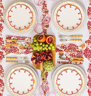 Rosy Red Scalloped Lunch Plates on placemats around a table with fruit on a board, seen from above