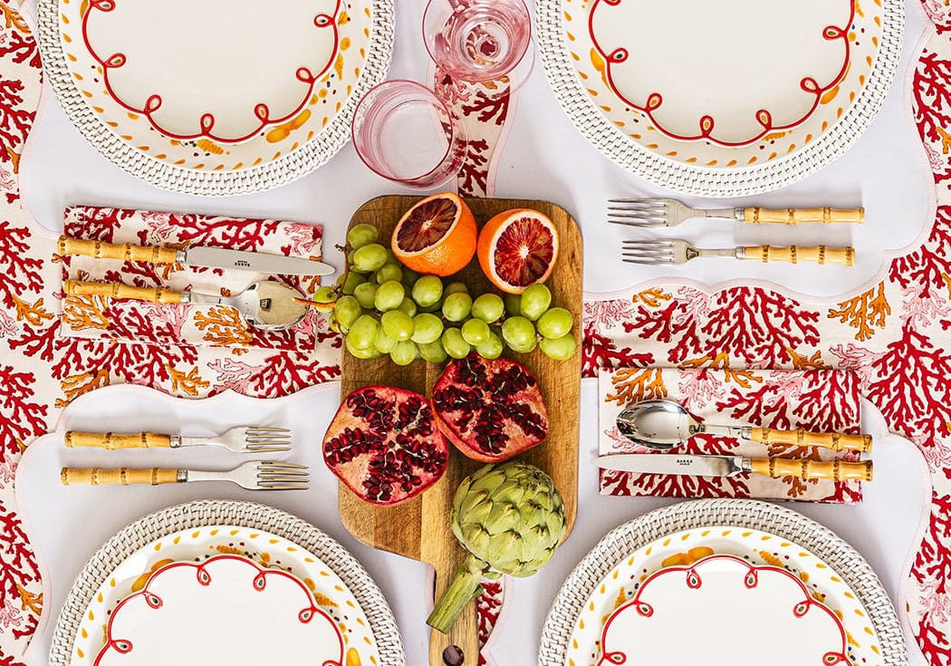 Rosy Red Scalloped Lunch Plates on placemats around a table with fruit on a board, seen from above