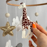 Safari Dreams Felt Cot Mobile with a hand holding the felt giraffe, showing its brown patches and stitched edges