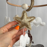 Safari Dreams Felt Cot Mobile with a hand holding a gold glitter star and a white cloud, close up