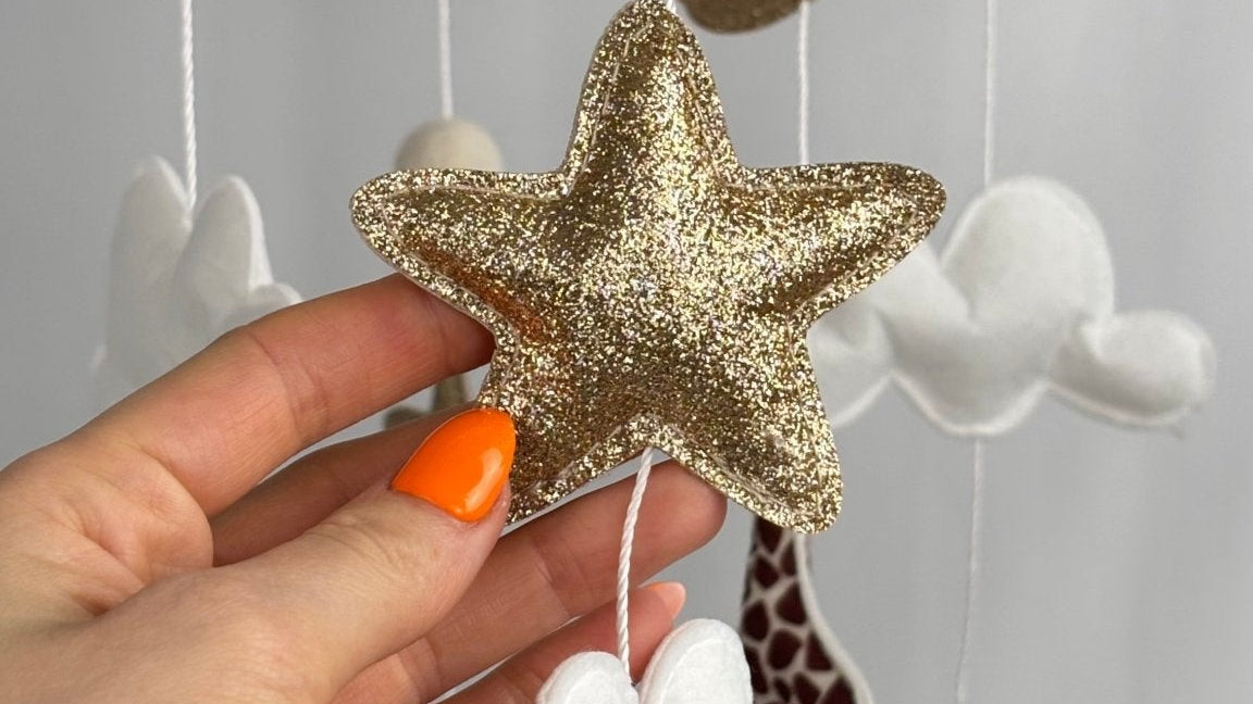Safari Dreams Felt Cot Mobile with a hand holding a gold glitter star and a white cloud, close up