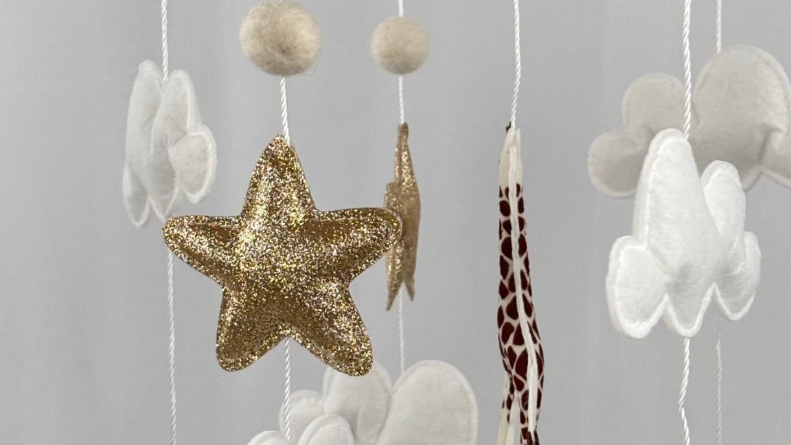 Safari Dreams Felt Cot Mobile side angle showing the rhino, gold star, clouds, giraffe and zebra hanging from the ring