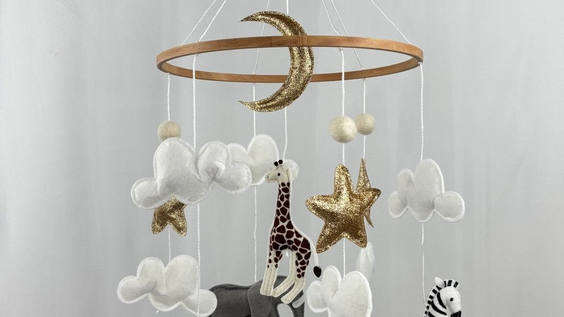 Safari Dreams Felt Cot Mobile hanging from a wooden arm and round wooden music box, full view against a pale backdrop