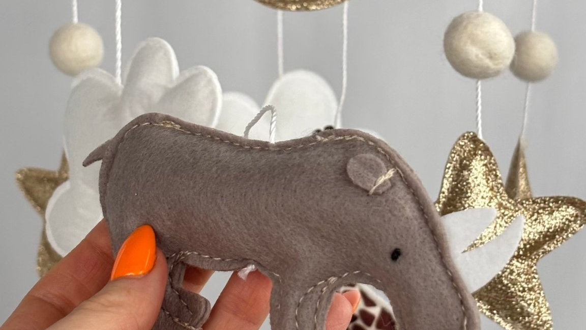 Safari Dreams Felt Cot Mobile with a hand holding the grey-brown felt rhino with stitched edges