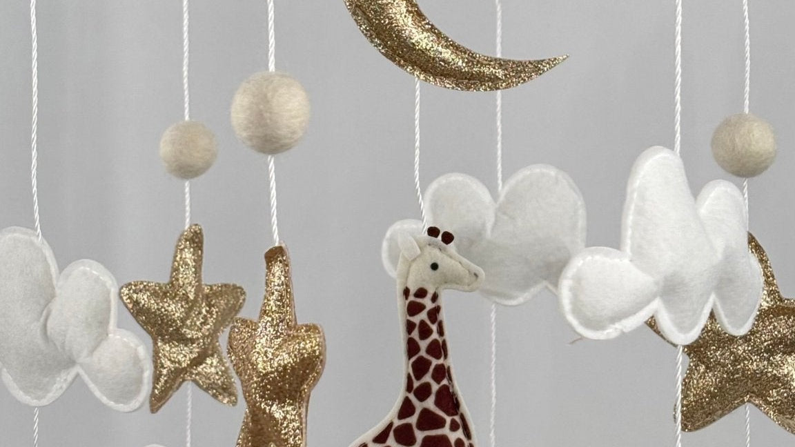 Safari Dreams Felt Cot Mobile close up of the gold glitter moon, stars, white clouds, giraffe and elephant