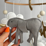 Safari Dreams Felt Cot Mobile with a hand holding the grey felt elephant with a white tusk and stitched edges