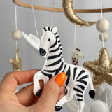Safari Dreams Felt Cot Mobile with a hand holding the black and white felt zebra in a prancing pose