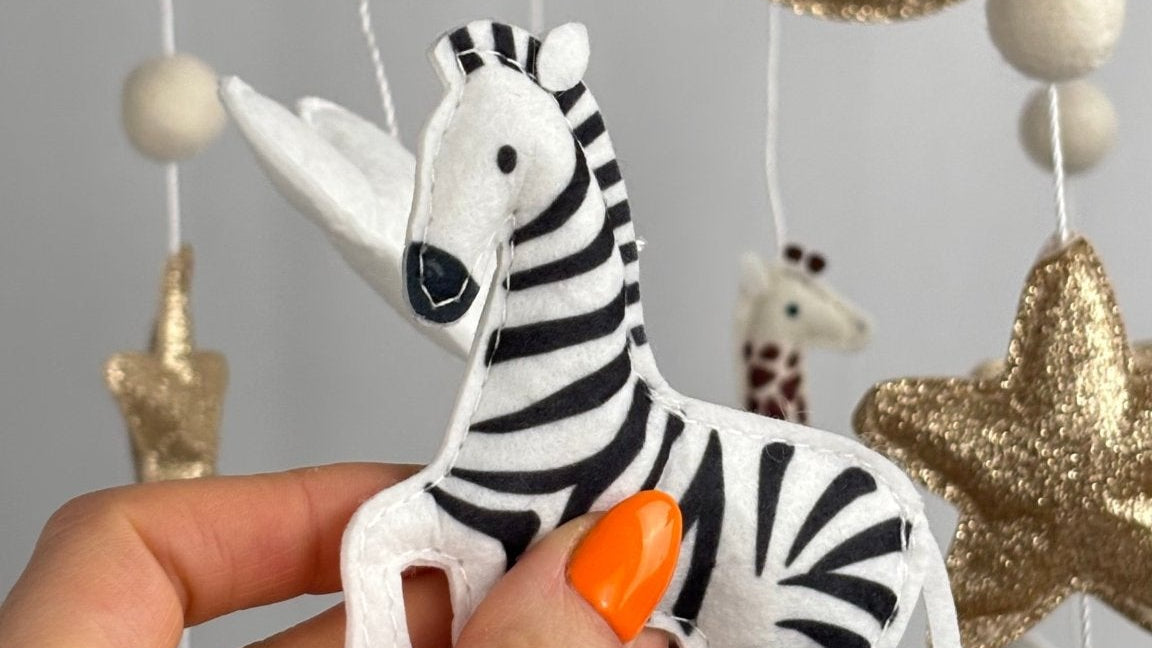 Safari Dreams Felt Cot Mobile with a hand holding the black and white felt zebra in a prancing pose