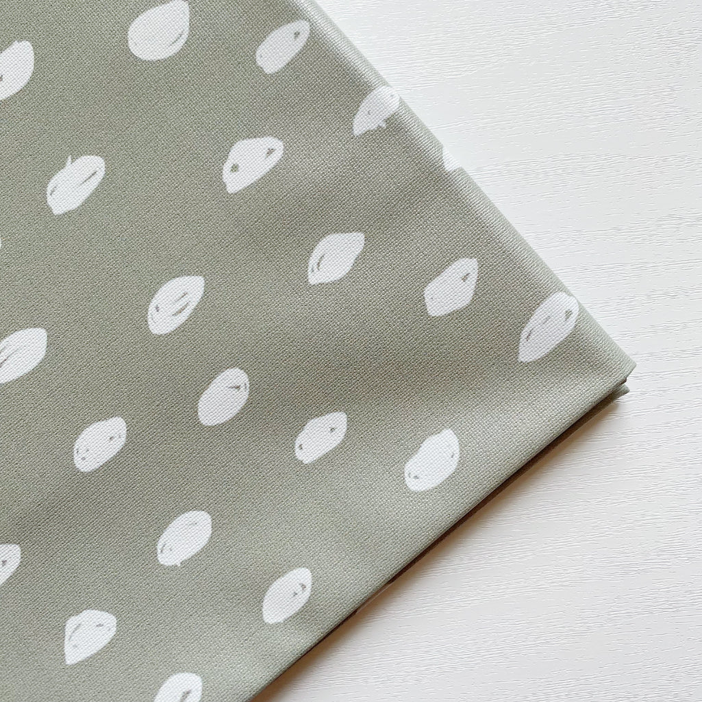 Splash Mat Sage Spots, close-up of the folded corner showing white hand-drawn spots on sage green