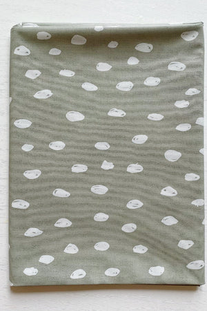 Splash Mat Sage Spots, folded flat on a white wooden surface showing the spotted pattern