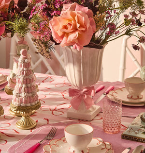 Pretty in Pink Scalloped Lunch Plates stacked under a cup on a pink table setting with a vase of roses and a macaron tower