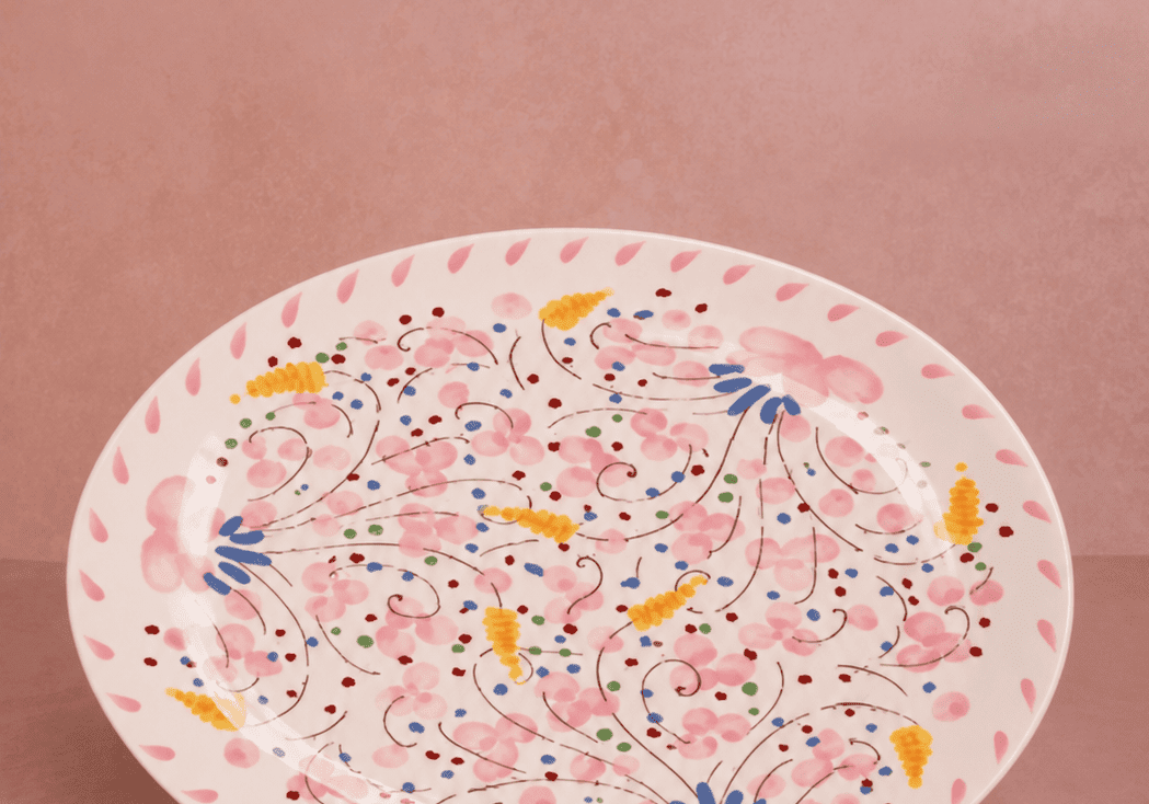 Springtime Meadow Oval Serving Plate with a hand-painted pink floral pattern and pink petal border on a pink backdrop