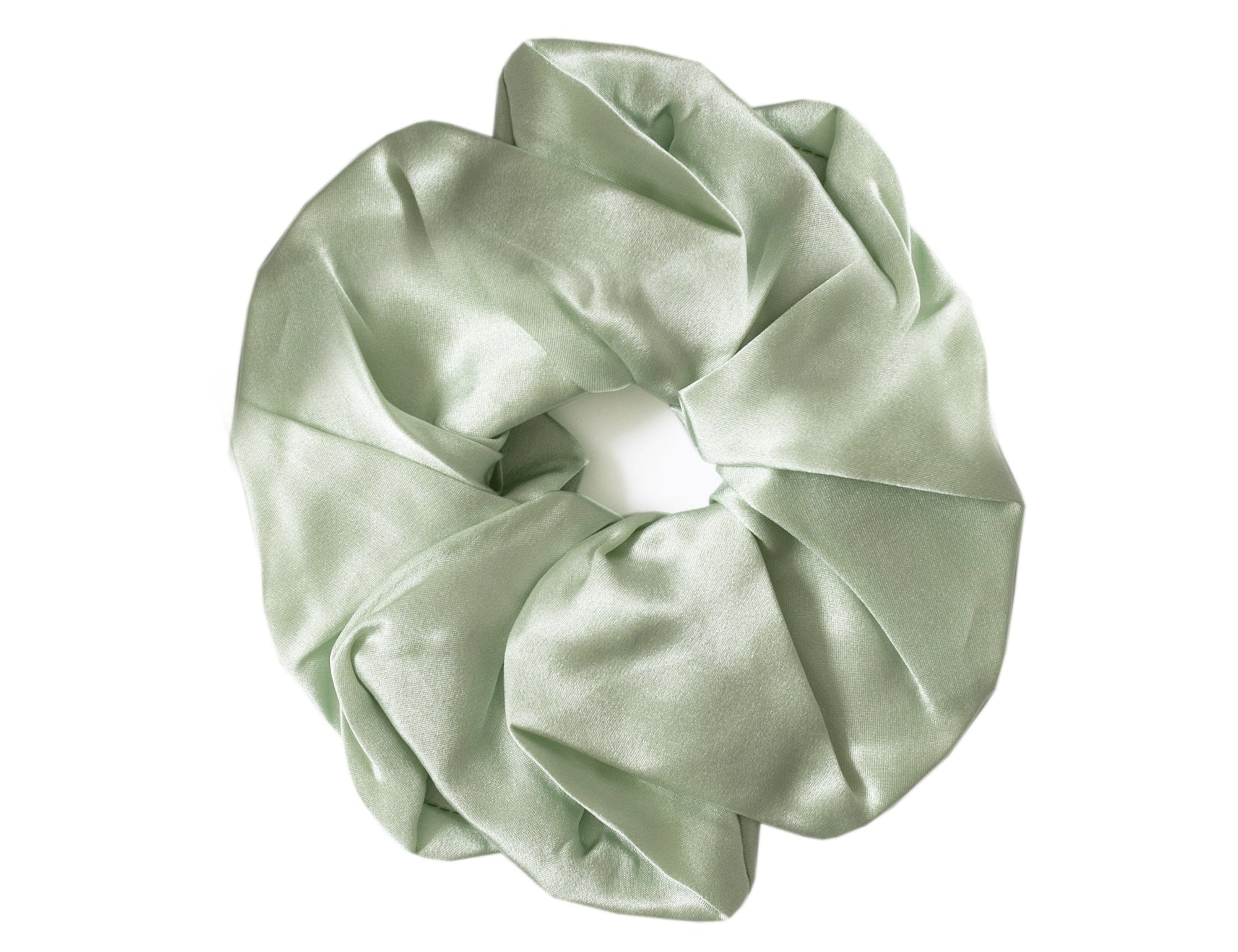 A sage green satin hair scrunchie with a gathered, pleated texture and a white elastic center band, shown on a plain white background.