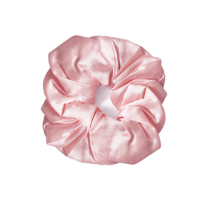 A single light pink satin hair scrunchie centered on a plain white background.