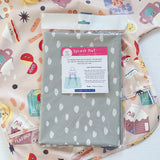 Splash Mat Sage Spots, in its packaging lying on a pink food-print sleeved bib