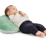 Sophie la girafe Cosy Play Cushion, baby reclining against the plain green quilted back of the cushion