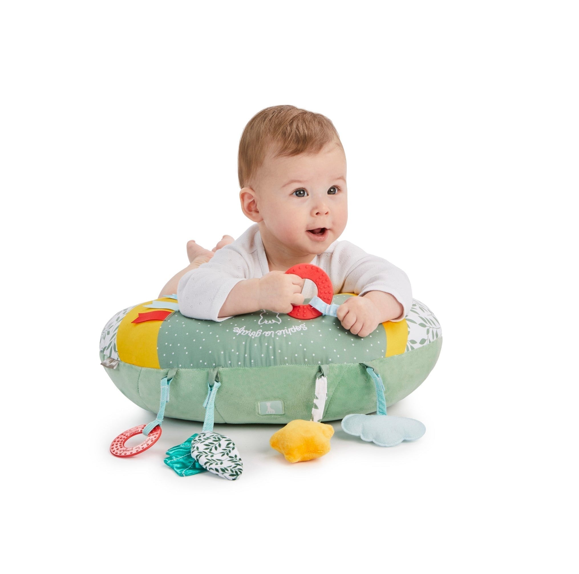 Sophie la girafe Cosy Play Cushion, baby lying on tummy over the cushion holding the red ring toy