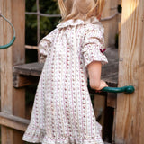 Beatrice Rose Stripe nightie, back view of a child holding a green handle, showing the sleeve and frilled hem