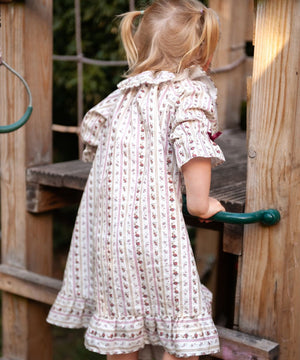 Beatrice Rose Stripe nightie, back view of a child holding a green handle, showing the sleeve and frilled hem