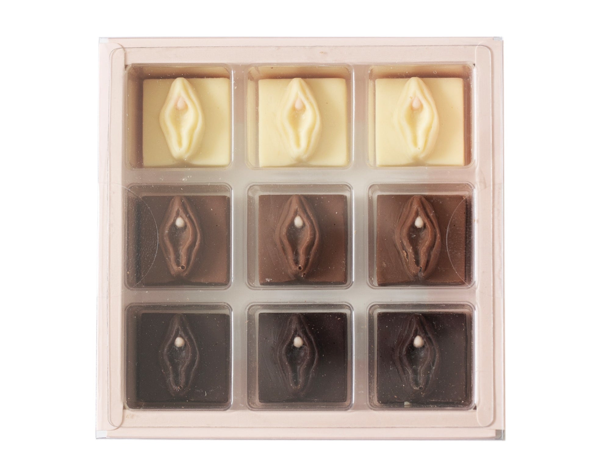 A 9-piece chocolate assortment in a clear plastic tray, featuring three milk chocolate pieces with a central heart and six dark chocolate pieces with a central eye, in cream and dark brown tones.