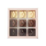 A 9-piece chocolate assortment in a clear plastic tray, featuring three milk chocolate pieces with a central heart and six dark chocolate pieces with a central eye, in cream and dark brown tones.