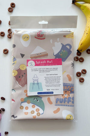 Splash Mat Snack Time folded in its clear packaging with a label, beside bananas and chocolate cereal rings