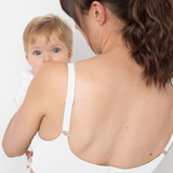 Woman wearing a white bra holding a baby against a white background