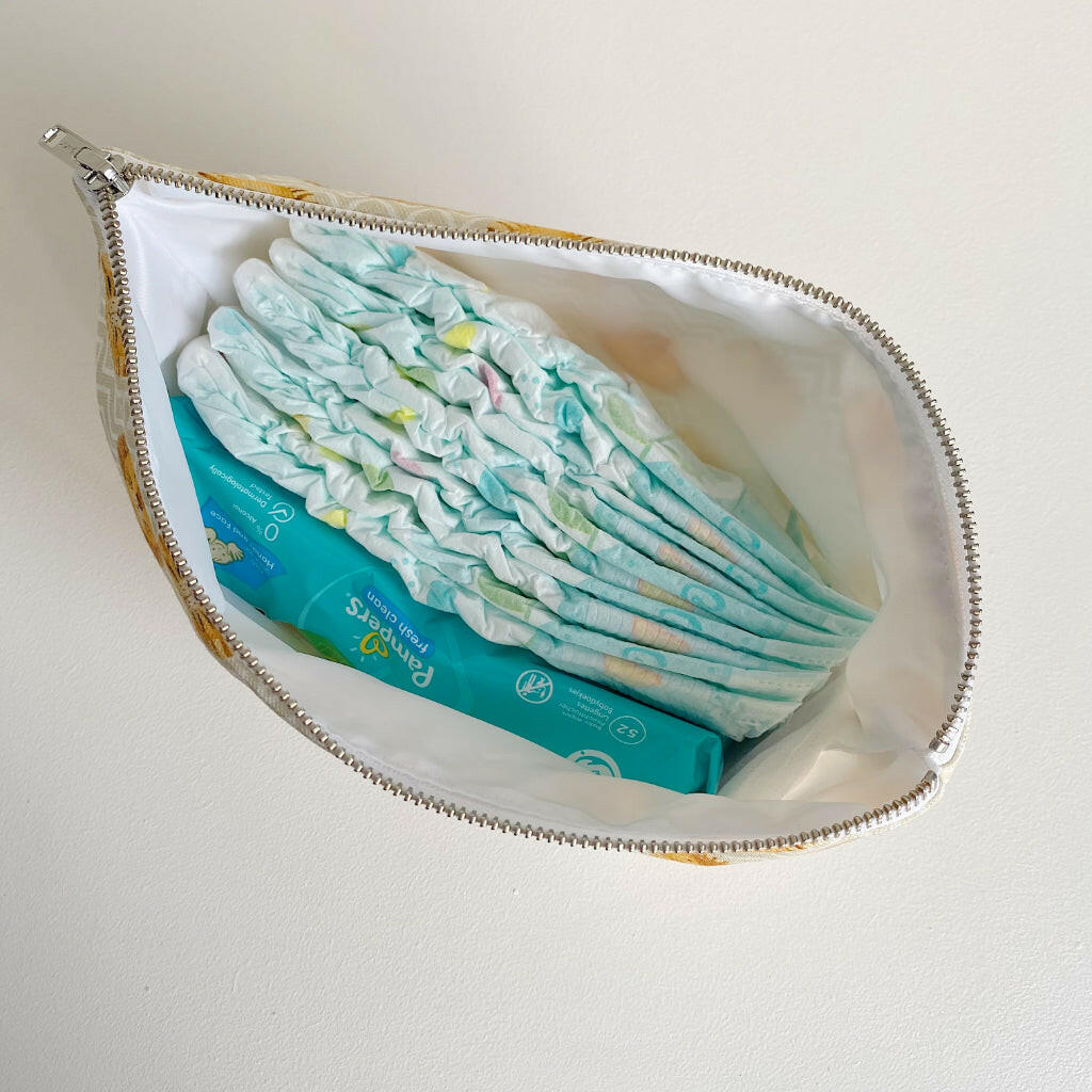 Nappy wallet in Leo lion print, unzipped from above with nappies and a pack of wipes inside the white lining