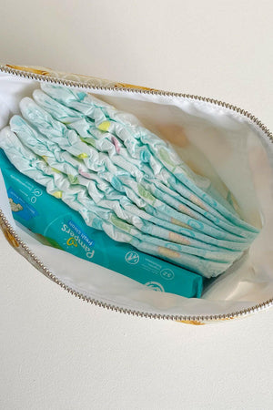 Nappy wallet in Leo lion print, unzipped from above with nappies and a pack of wipes inside the white lining