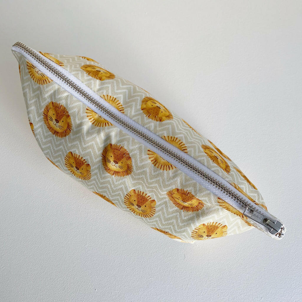 Nappy wallet in Leo lion print, top-down view of the closed pouch lying flat showing the long silver zip